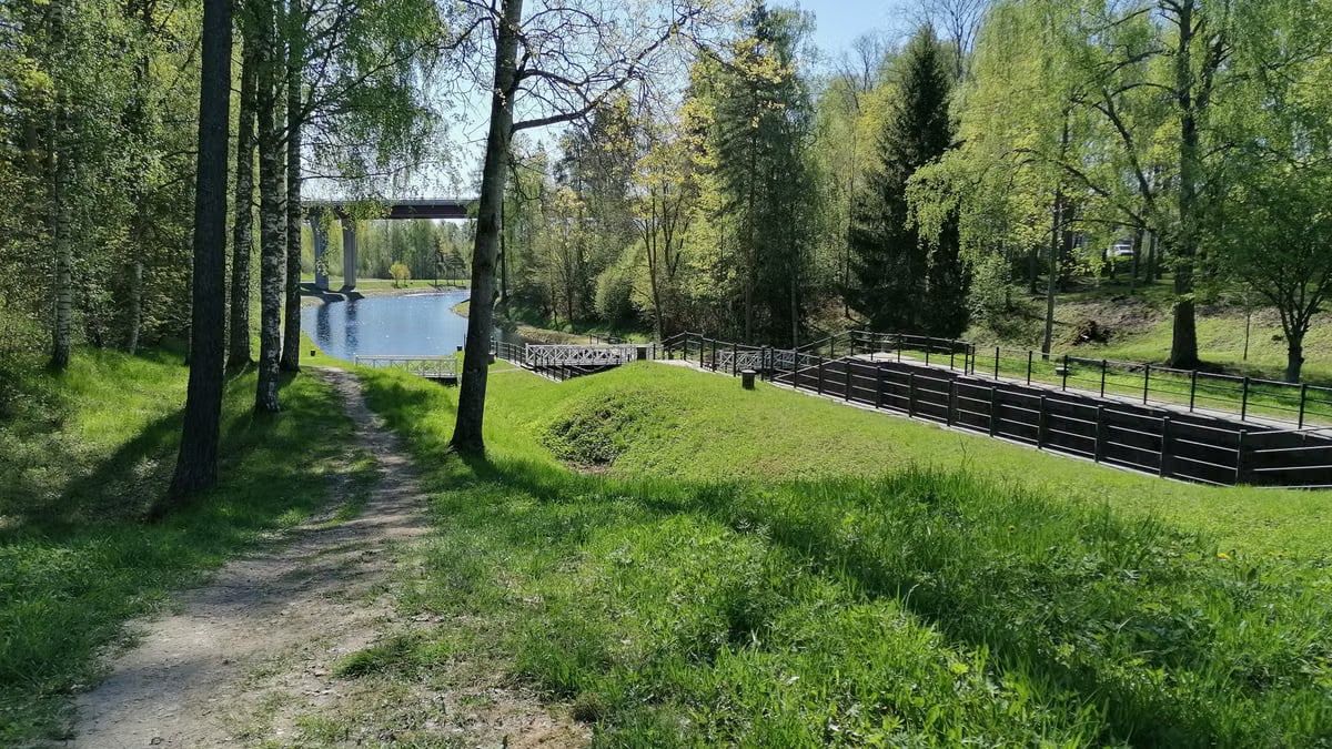 Idyllic spring landscape with a path through lush greenery by a calm river.